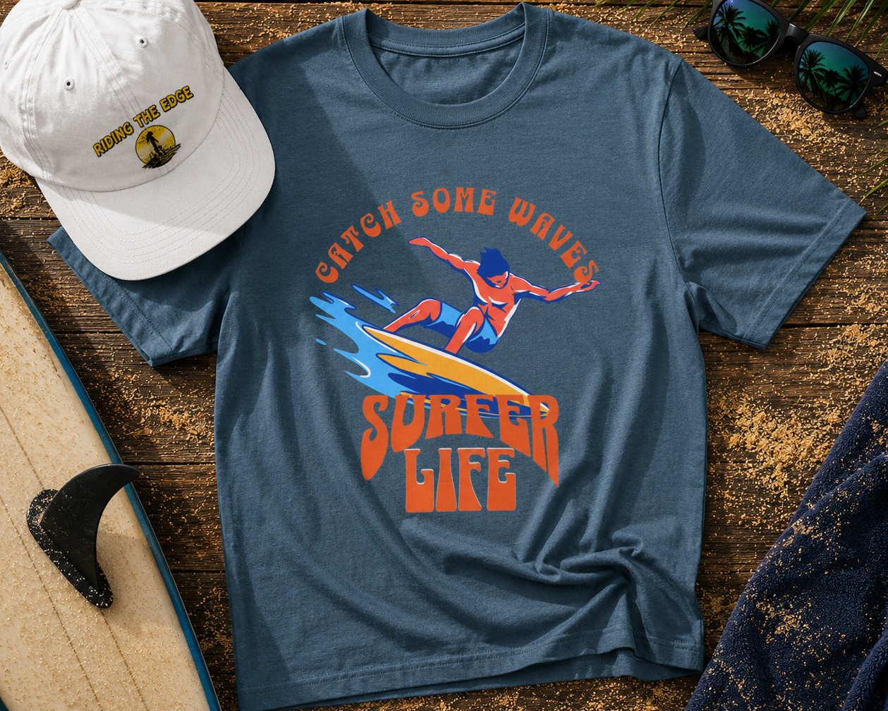 Blue t-shirt with 'Catch Some Wave, Surfing Life' design, white cap, sunglasses, and surfboard on wooden surface
