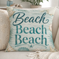 Square decorative pillow with teal "Beach" lettering on aqua shell-and-starfish printed fabric