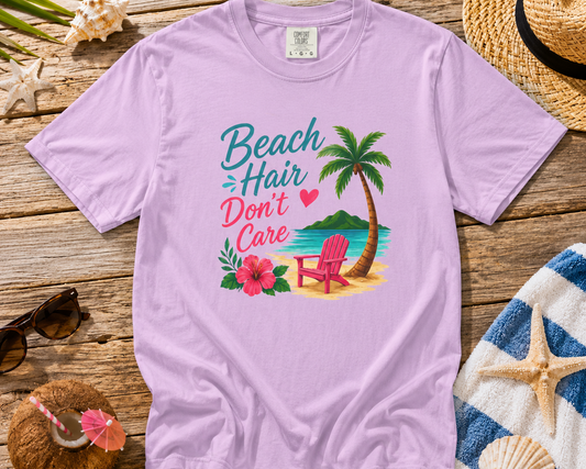 Purple t-shirt with beach-themed design on a wooden surface with beach accessories.