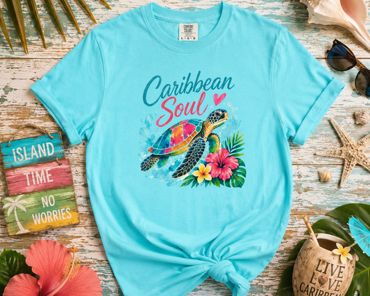 Turquoise t-shirt with a turtle graphic and 'Caribbean Soul' text on a wooden surface with tropical decorations.