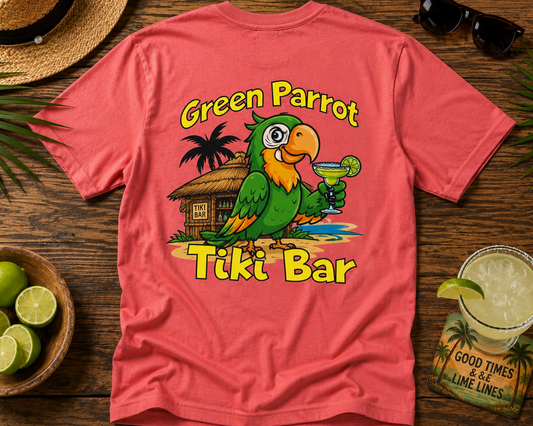 Pink t-shirt with a green parrot graphic and 'Green Parrot Tiki Bar' text on a wooden surface with a drink and limes.