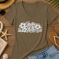 A women's short-sleeve V-neck t-shirt in heathered brown, featuring a white graphic print of tropical flowers and flip-flops across the chest, displayed on a clean white background.