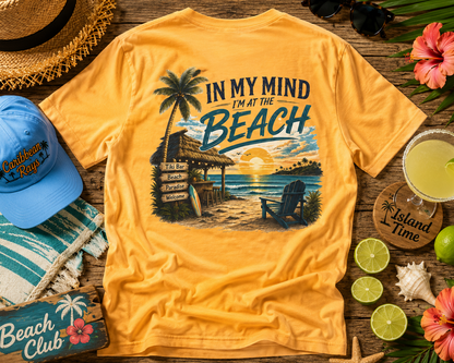 Yellow t-shirt with beach-themed design on a wooden surface with accessories.