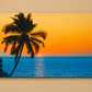 A rectangular wall art print showing a tropical sunset scene with a dark palm tree silhouette, blue ocean water, and a glowing orange sky, mounted against a beige wall.