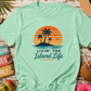 Mint green t-shirt with 'Livin' the Island Life' design on a wooden surface with tropical accessories.