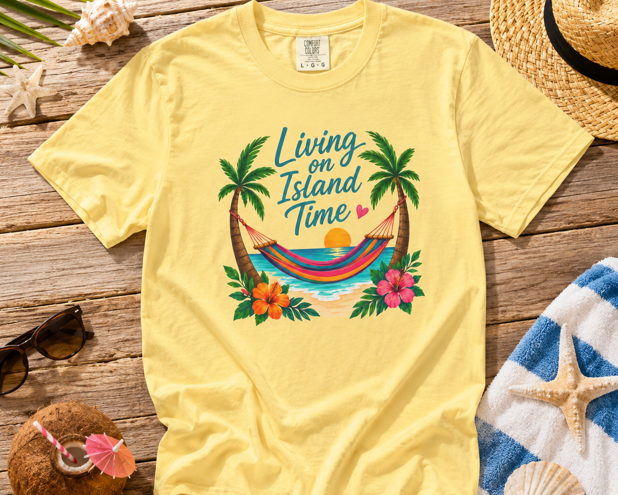 Yellow t-shirt with tropical design on a wooden surface with beach accessories.