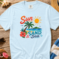 White t-shirt with 'Sun, Sand & Sea' design on a wooden surface with beach-themed accessories.