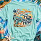 Teal t-shirt with 'Sunshine and Flip Flops' design on a beach setting with flip-flops, sunglasses, and a hat.