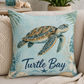 Square throw pillow on a sofa with sea turtle artwork and "Turtle Bay" lettering