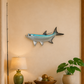 Decorative fish wall art above a wooden console table with a lamp, books, and plant.