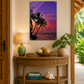 Decorative wall art of palm trees and sunset over a table with decor items.