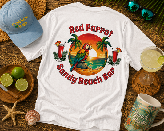 White t-shirt with 'Red Parrot Sandy Beach Bar' design, blue cap, limes, and a mug on a wooden surface.