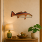 Decorative fish on a wall above a wooden console table with a lamp and books.