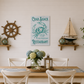 Dining room with a wooden table, chairs, and decorative elements including a crab shack sign and ship wheel.