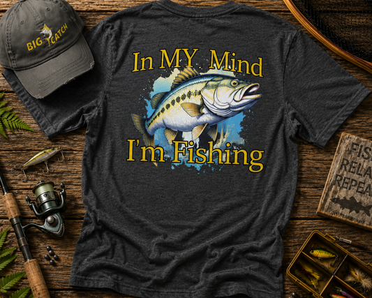 Dark gray t-shirt with fishing graphic and text on a wooden surface with fishing gear.